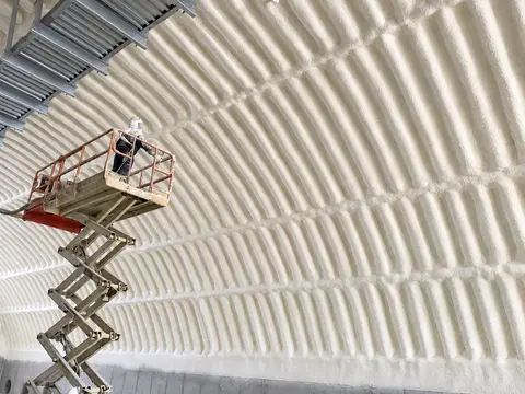 Worker on a lift inside an insulated arched building